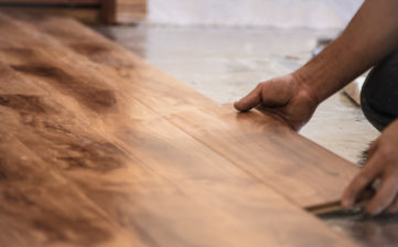 Man installing wood flooring in home.
