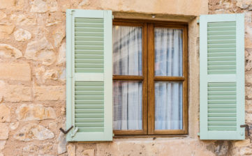 Detail view of open wooden window shutters and stone wall